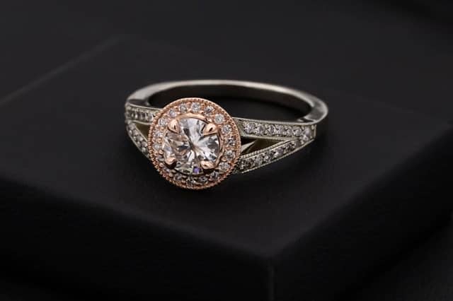 Two-tone ring: a white metal pavé band with a rose gold halo around a round diamond