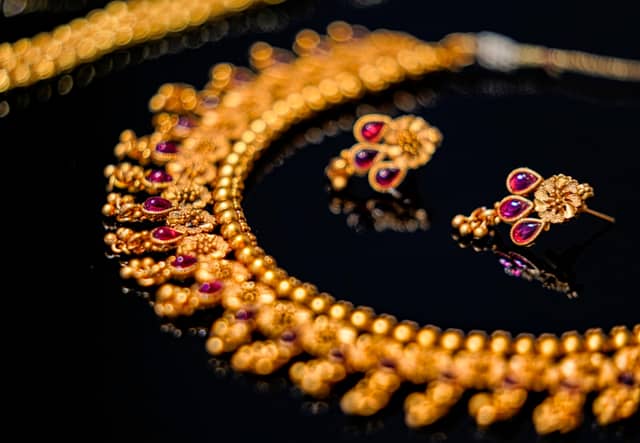 Gold necklace and matching drop earrings set with pink-red cabochon stones